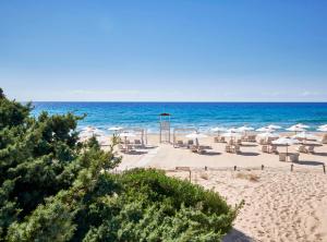 奇亚Baia Di Chia Resort Sardinia, Curio Collection By Hilton的海滩上设有椅子和遮阳伞,还有大海