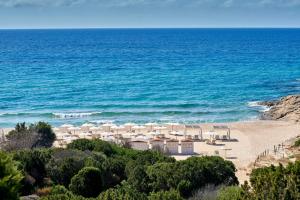 奇亚Baia Di Chia Resort Sardinia, Curio Collection By Hilton的海滩上设有白色的遮阳伞和海洋