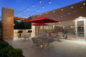 东港Home2 Suites By Hilton East Haven New Haven的一个带桌椅和红色遮阳伞的庭院