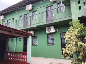 马瑙斯Residencial Andréa House的绿色建筑,设有窗户和阳台
