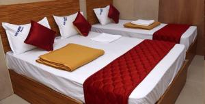 孟买HOTEL COSTA DEL的配有红色和白色枕头的客房内的两张床