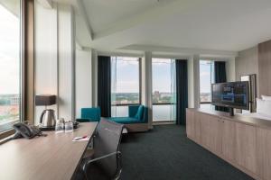阿姆斯特丹Leonardo Hotel Amsterdam Rembrandtpark的办公室设有书桌、电视和窗户。