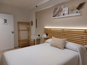 奥维多Pensión Cabezas Oviedo的卧室配有白色的床和木制床头板