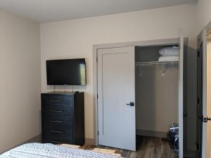 特拉弗斯城Modern Condo 210 Just Blocks from Lake Michigan的一间卧室配有一张床、一台电视和一个衣柜