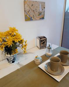 布宜诺斯艾利斯Lavalle Studio Buenos Aires的一张桌子,上面有两杯,花瓶有黄色的花