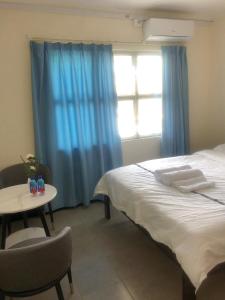 南迪CC airport rooms的一间卧室配有一张床、一张桌子和一个窗户。