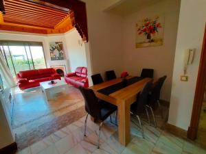 马拉喀什Appartements de charme à la palmeraie的客厅配有桌子和红色沙发