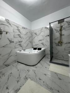 比斯特里察鹏西尼亚老警长汽车旅馆的白色的浴室设有浴缸和淋浴。
