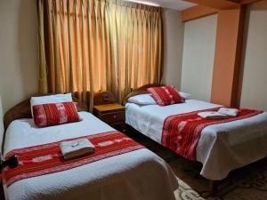 库斯科可库瓦赛酒店的酒店客房带两张红色和白色的床单