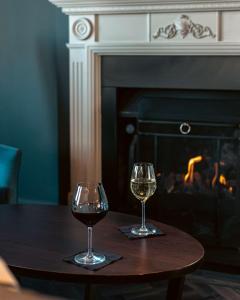 伦敦伦敦希尔顿逸林酒店 - 港口河畔的壁炉前的桌子上放着两杯葡萄酒