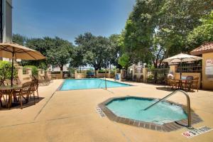 圣安东尼奥Drury Plaza Hotel San Antonio Airport的一个带桌椅和遮阳伞的游泳池