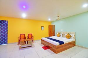BhadrakSPOT ON Mahaveer Resort的一间卧室设有一张床铺、一张桌子和黄色的墙壁