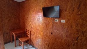 奥克萨潘帕Hospedaje El Manantial的配有电视、椅子和桌子的房间