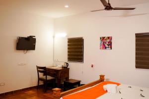 马拉利库兰Marari Beach Palace的一间卧室配有一张床、一张书桌和一台电视