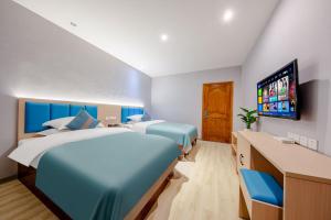昆明曼朵酒店(昆明长水国际机场店)的一间卧室配有两张床和一台平面电视
