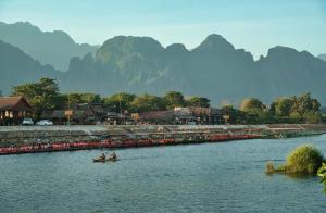 万荣Vang Vieng Chanthala Hotel 1的两人在一条有山底的河上乘船