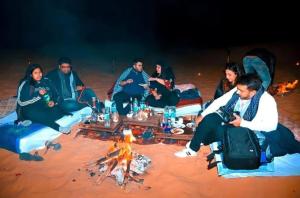 斋沙默尔Sam dunes desert safari camp的一群人围坐在火炉旁