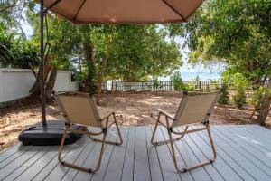 苏梅岛Brand New Beachfront & Secluded Tiny House的两把椅子坐在甲板上,放在伞下
