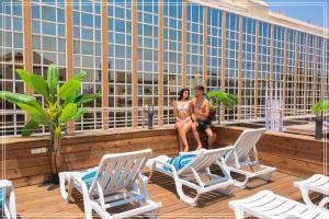 特拉维夫Dream Beach Hotel And Spa的两名身着泳衣的女性坐在屋顶甲板上