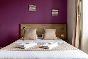 Plurien伯恩卡普酒店的紫色卧室,床上配有2条毛巾