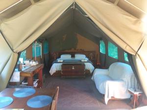 维德尼斯Wilderness Glamping Tents的带2张床和桌子的帐篷客房