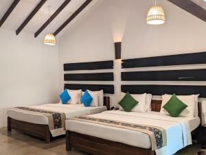 锡吉里亚Pinthaliya Resort的配有两张床铺的蓝色和绿色枕头