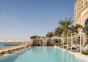多哈Four Seasons Resort and Residences at The Pearl - Qatar的棕榈树海滩旁的游泳池