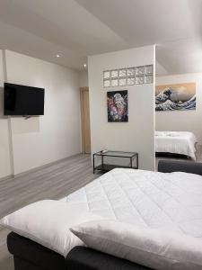 恩波利7Suites的卧室配有白色的床和平面电视。