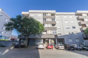 布拉加Quinta da Armada, Apartamento em Braga by House and People的一座大型建筑,前面有汽车停放