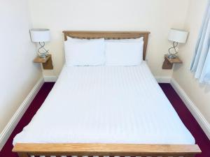 滕比The Belgrave Hotel Tenby的一间卧室配有一张带白色床单和两盏灯的床。