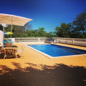 圣巴巴拉-迪内希Vila Flora的一个带桌子和遮阳伞的游泳池