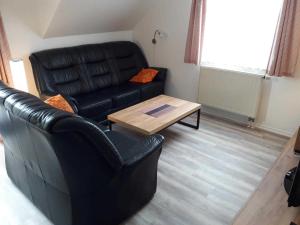 卡尔斯哈根Fewo Sommergarten 4010_MANT的客厅配有黑色真皮沙发和咖啡桌