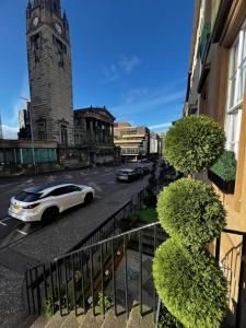格拉斯哥Amani Apartments - Glasgow City Centre的一辆白色汽车沿着钟楼街道行驶