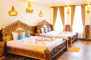 Phumĭ Puŏk ChăsPuok Hotel的卧室设有两张床,铺有木地板,设有窗户。