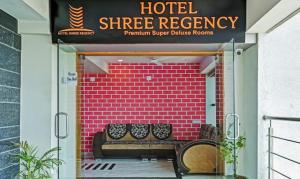 艾哈迈达巴德Hotel Shree Regency Ahmedabad的标志下带长凳的酒店入口