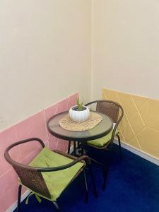 迪拜Salahuddin Metro Home Stay的一张桌子,上面有两把椅子和一个花瓶