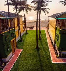 阿贡达The O2H Agonda Beach Resort的海滩前种有棕榈树的草坪