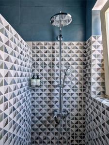纳乌萨Villa Maria - Naoussa Squares Blue & Gold Suite的浴室铺有黑白瓷砖,设有淋浴。