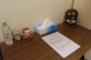 大阪Niji Homestay的一张桌子,上面放着一盒纸巾和一瓶水