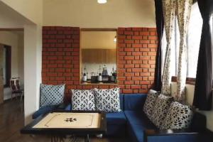 浦那Sadashiv Bungalow - Kudje,3BHK with swimming pool的客厅设有蓝色的沙发和砖墙