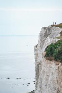 博雷The Lighthouse Cabin的两个人站在靠近海洋的悬崖上