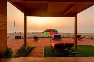 阿贡达The O2H Agonda Beach Resort的海滩前的一张桌子和一把色彩缤纷的遮阳伞
