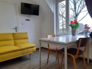 比伦Pension Het Hoefijzer的客厅配有桌子和黄色沙发