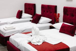 都拉斯Andor Luxury Hotel的红色和白色的客房内的三张床
