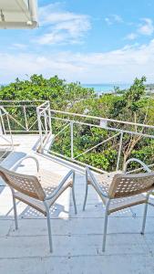 读谷村珊瑚花园七池酒店的两把椅子坐在一个有海洋背景的庭院里