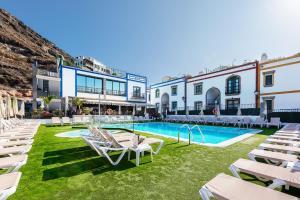 莫甘海滩Billy's Puerto de Mogán Apartments by LIVVO的一个带椅子的庭院和一个游泳池