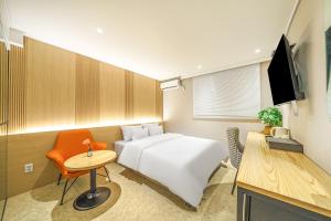 仁川市No 25 Hotel Dongam Branch的一间酒店客房,配有一张白色的床和一张书桌