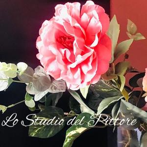 瓦斯托Lo Studio del Pittore的花瓶里一朵粉红色的花,有叶子