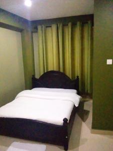 坎帕拉Suzie hotel 15 rubaga road , old Kampala的床上床,坐在带窗帘的房间