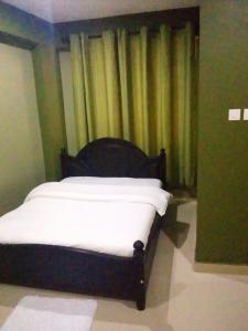 坎帕拉Suzie hotel 15 rubaga road , old Kampala的配有窗帘的客房内的一张带白色床单的床